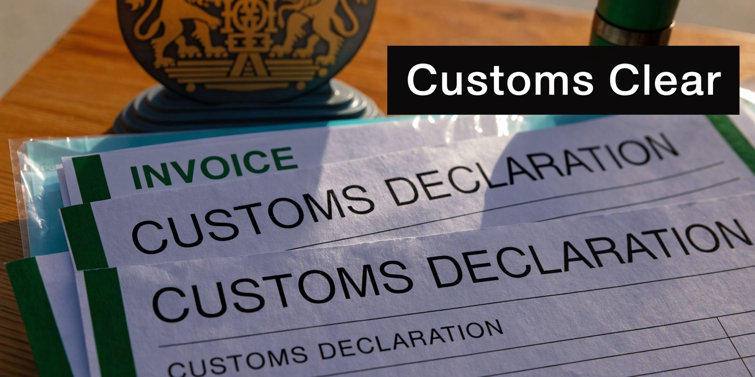A stack of paperwork including custom declaration and invoice forms resting on a wooden desk.