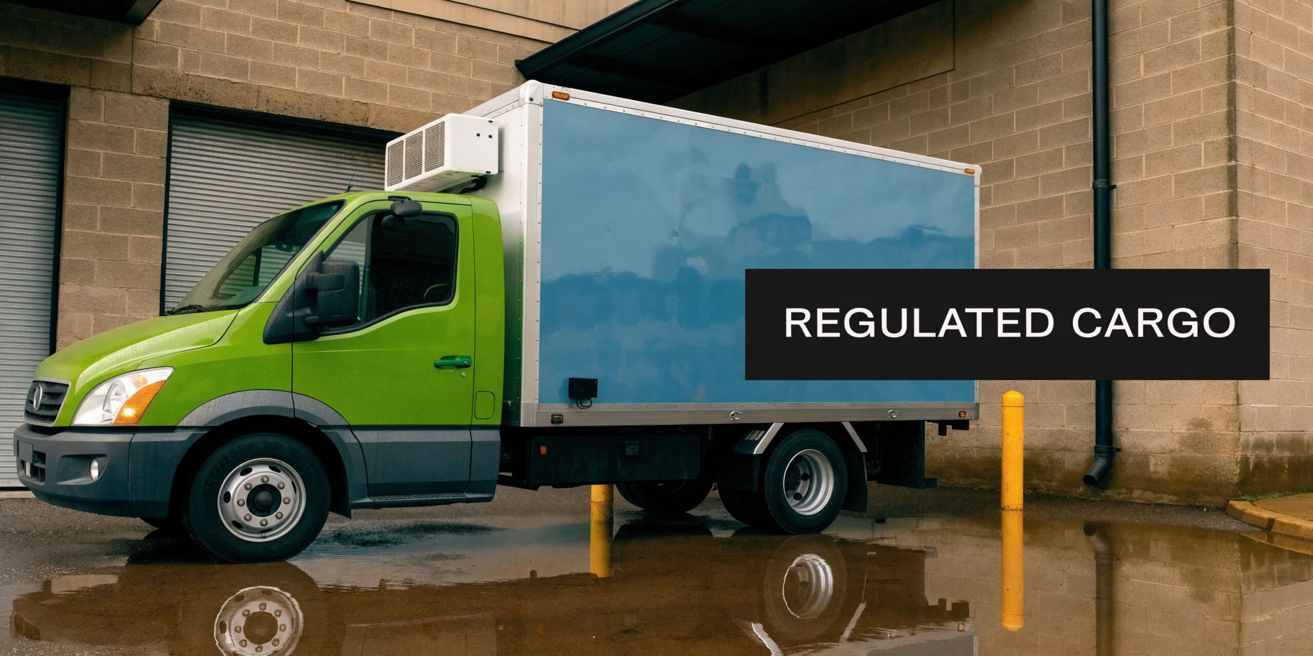 A lime green and blue commercial refrigerated delivery truck parked outside a warehouse with puddles nearby.
